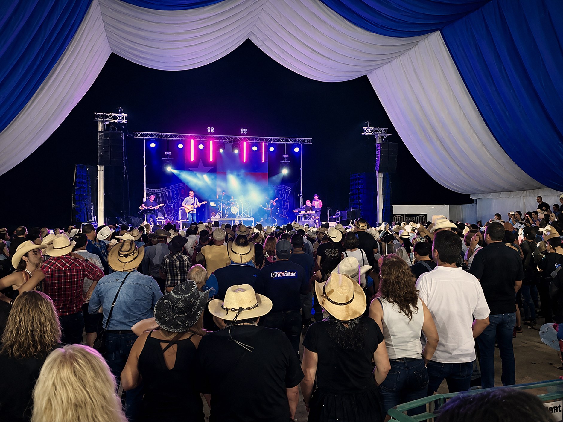 Carpa plena de públic amb barrets de cowboy davant d'un concert de country en directe